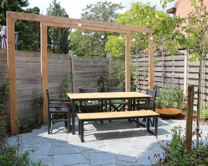 Een weelderige stadstuin met pergola en flagstones